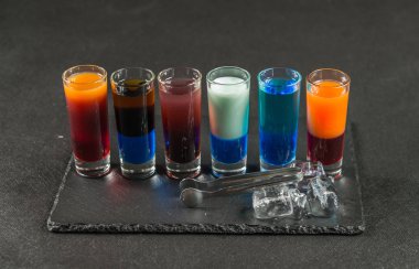 altı farklı renkli çekim içecek, üzerinde siyah bir taş pla dizilmiş