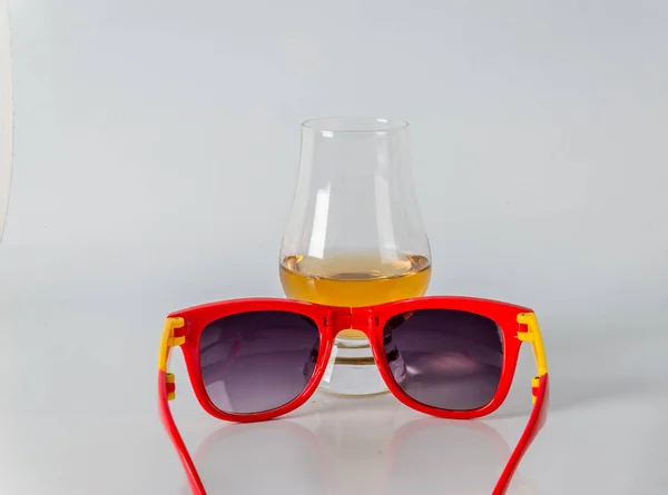 Delicious single malt whiskey glass with sunglasses on a white b — Stock Photo, Image