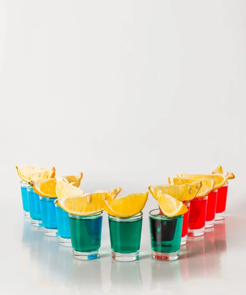 Одиннадцать цветных напитков, красный, синий и зеленый камикадзе, четвертаки — стоковое фото