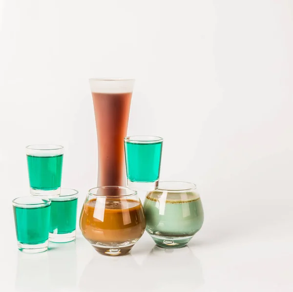 Sete tiros da bebida da cor, formas de vidro diferentes, verde e marrom — Fotografia de Stock