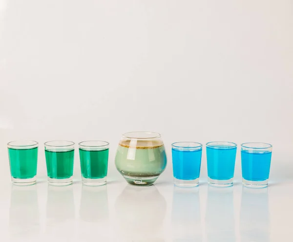 Seven color drink shots, different glass shapes, blue, green and
