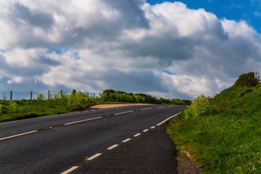 Boş asfalt yol, yeşil bir omuz, etrafa okyanus, 