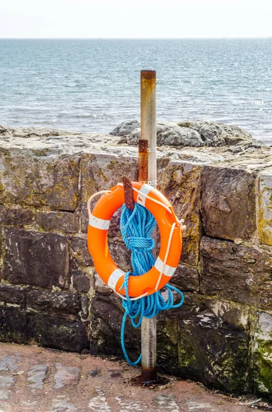 Oranžové záchranný kruh na kamenné zdi, zachránit, modré lano, ocean shore — Stock fotografie