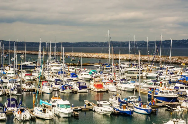 Boats anchored in a small harbor, in the background stone promen