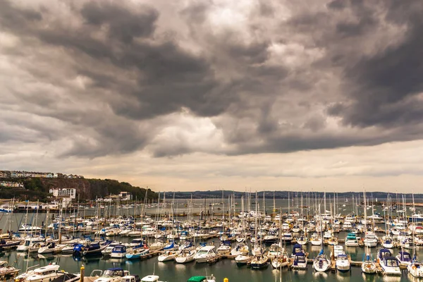 Boats anchored in a small harbor, in the background stone promen