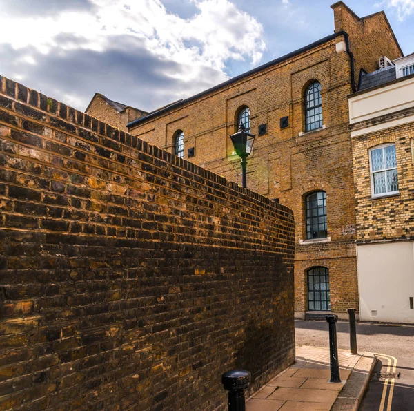 Typical old English buildings, low brick buildings across a narr