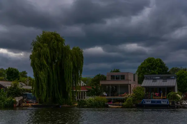 Amplio río y casas en la orilla, barcos amarrados, vegetati verde —  Fotos de Stock
