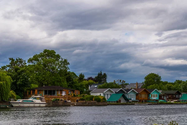 Широка річка і будинки на березі, причальні човни, зелений вегетаріанський — стокове фото