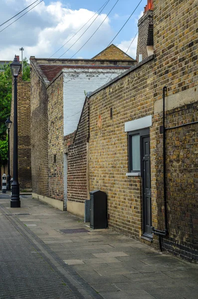 Edifícios ingleses velhos típicos, edifícios baixos do tijolo através de um narr — Fotografia de Stock