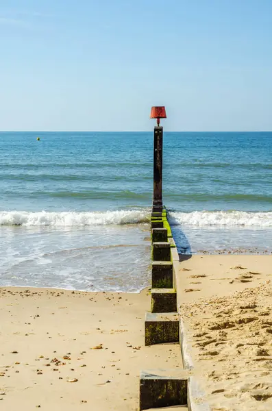 Montones de muelles en una playa de arena, océano azul y arena amarilla, soleado —  Fotos de Stock