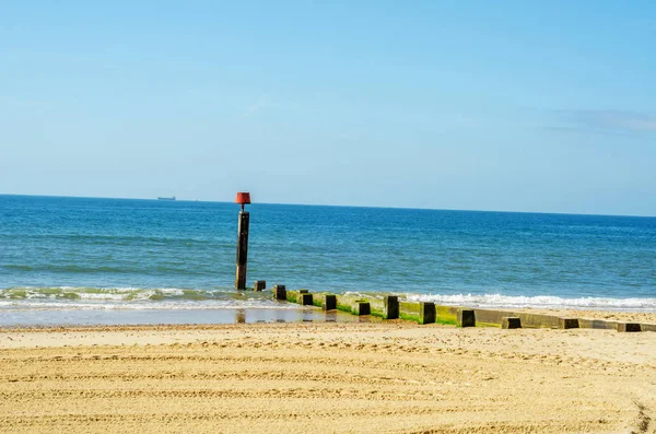 Αποβάθρα πασσάλους σε μια αμμώδη παραλία, μπλε ωκεανό και κίτρινη άμμο, ηλιόλουστες — Φωτογραφία Αρχείου