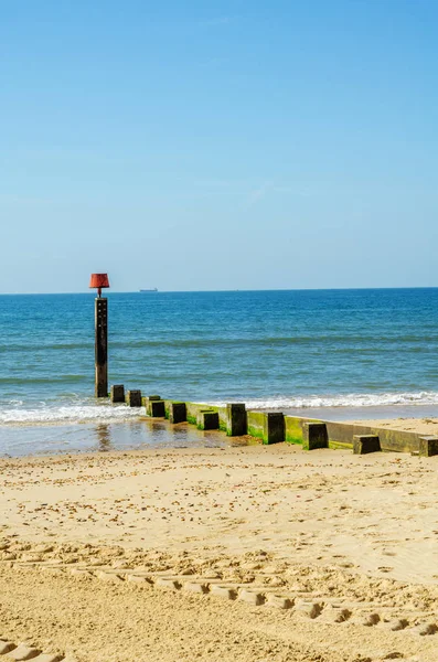 Pali di pontile su una spiaggia sabbiosa, oceano blu e sabbia gialla, soleggiato — Foto Stock