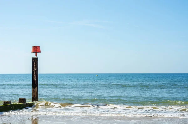 Pali di pontile su una spiaggia sabbiosa, oceano blu e sabbia gialla, soleggiato — Foto Stock