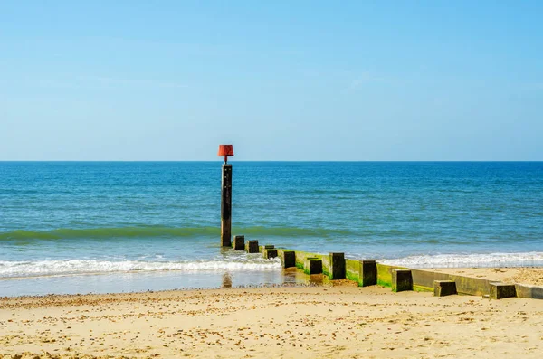 Pieux de quai sur une plage de sable, océan bleu et sable jaune, ensoleillé — Photo