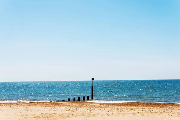 Montones de muelles en una playa de arena, océano azul y arena amarilla, soleado —  Fotos de Stock