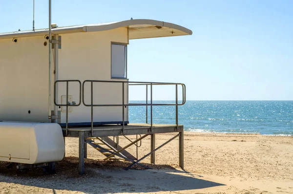 Beyaz kurtarma kulübe güvenli bir kumlu plajda sakin okyanus ile bir olmak