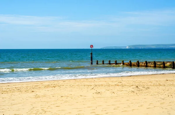 Pilhas de doca em uma praia de areia, oceano azul e areia amarela, ensolarado — Fotografia de Stock