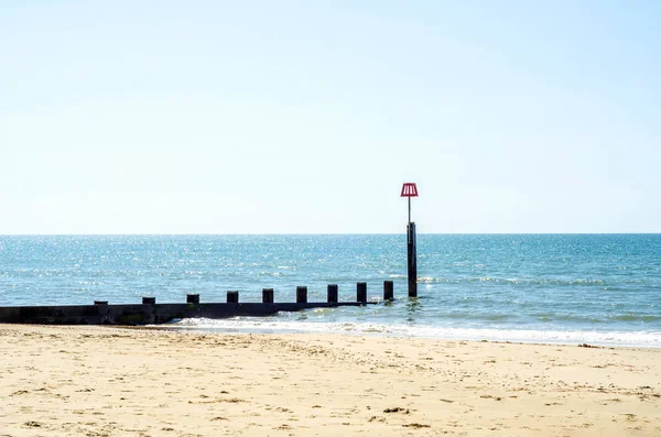 砂浜のビーチ、青い海と日当たりの良い黄色の砂に杭を固定します。 — ストック写真