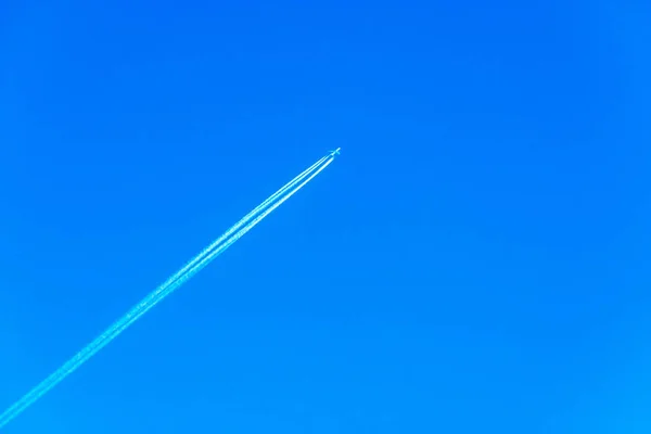 Flugzeug in Reiseflughöhe, Flugzeug mit Chemtrails am blauen Himmel — Stockfoto