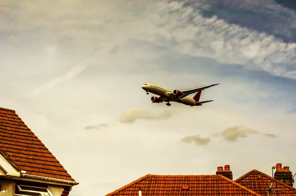 低住宅街の家の屋根の上を飛んで旅客機 — ストック写真