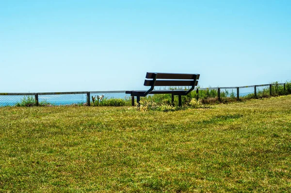 Banco vacío en una colina en la orilla del océano, vegetación verde exuberante , — Foto de Stock