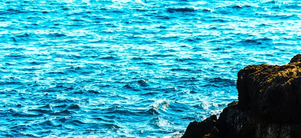 Ψηλό βράχο πάνω από τη θάλασσα, φόντο στη θάλασσα το καλοκαίρι, πολλοί πιτσίλισμα — Φωτογραφία Αρχείου