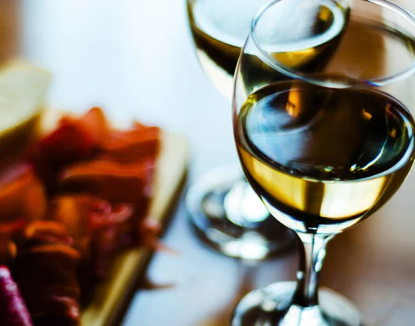 Bílé víno ve sklenici s předkrmy na dřevěném stole, soubor o — Stock fotografie
