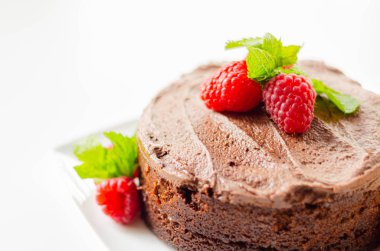 Belçika çikolatasına dayalı glütensiz yuvarlak pasta. Taze ahududu ve nane şekeri ile süslenmiş.