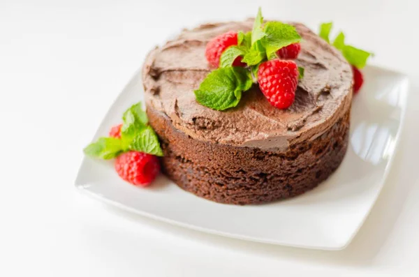 Gluten free tasty round cake based on Belgian chocolate decorated with fresh raspberries and mint, delicious sweets