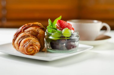 Tabakta lezzetli kruvasan, bir fincan kahve ve bir set...