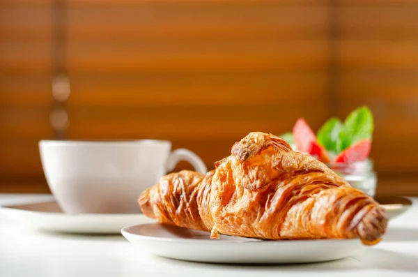Tabakta lezzetli kruvasan, bir fincan kahve ve bir set...
