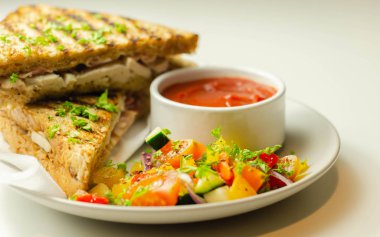 Tavuk göğsü ve kayın ağacı tütsülenmiş pastırmalı el yapımı sandviç. Karışık salata, domates sosu ve sağlıklı bir yemekle servis ediliyor.