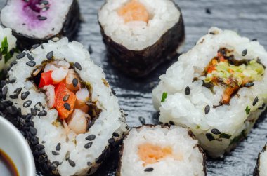 Sebzeli suşiyle balıklı suşiyi siyah taş tabakta karıştırın. Japon yemeği.