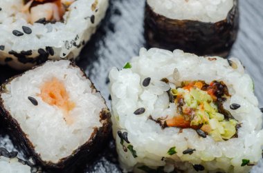 Sebzeli suşiyle balıklı suşiyi siyah taş tabakta karıştırın. Japon yemeği.