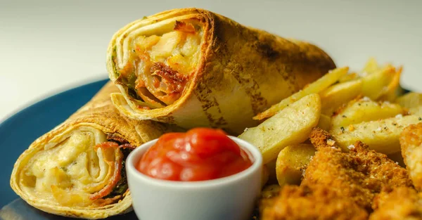 Tortilla wrap with chicken and beechwood smoked bacon served with chicken nuggets and chips, tasty food