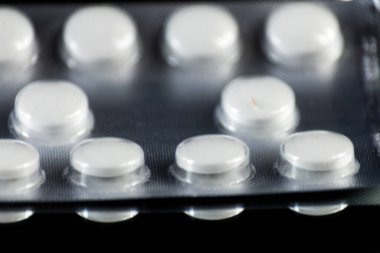 Tablet hap ilaç aynaya yansıyan bir siyah arka plan üzerinde dağınık