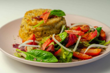 Eriyen çedar soslu füme mezgit balığı keki ve karışık salata, deniz ürünleri.