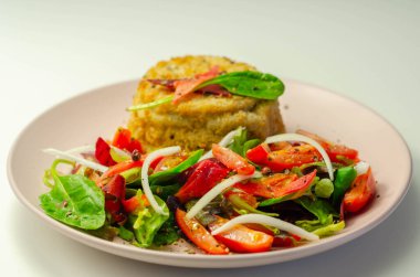 Eriyen çedar soslu füme mezgit balığı keki ve karışık salata, deniz ürünleri.