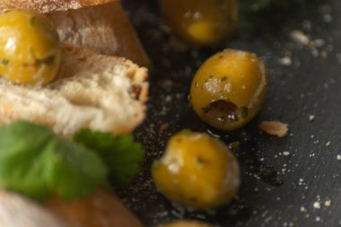 Taze baget ve sağlıklı yiyeceklerle servis edilen turşulu İspanyol yeşil zeytinleri.