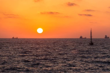 sarı-kırmızı günbatımı manzarası olan Yelkenli deniz üzerinde