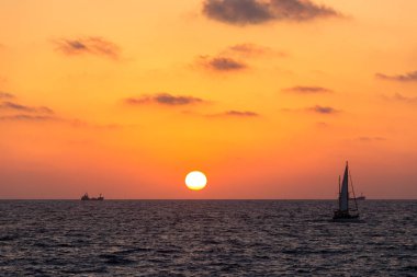 sarı-kırmızı günbatımı manzarası olan Yelkenli deniz üzerinde