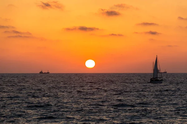 sarı-kırmızı günbatımı manzarası olan Yelkenli deniz üzerinde