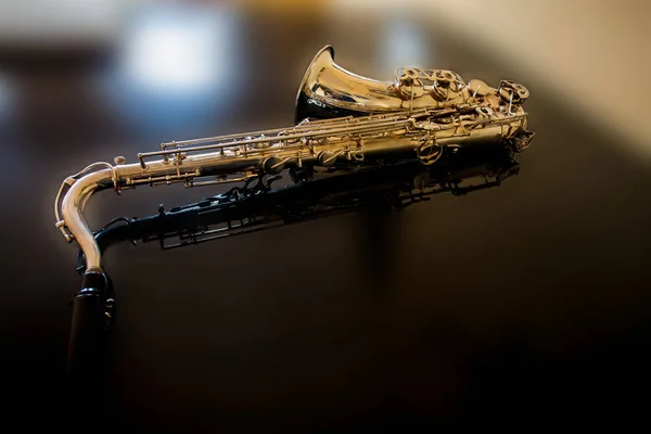 Saxophone tenor. Woodwind Classical Instrument. Jazz, blues, classics. Music. Saxophone on a black background. Black mirror surface. Music styles — Stock Photo, Image