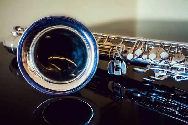 Saxophone tenor. Woodwind Classical Instrument. Jazz, blues, classics. Music. Saxophone on a black background. Black mirror surface. Music styles — Stock Photo, Image