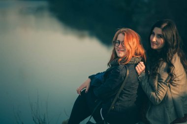 Kız günbatımı gölün kıyısında. Mutlu kız arkadaşlar bir ormanda günbatımında sarılma.