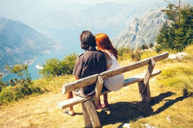 Bir kız bir adamla Kotor Koyu'ndaki bir bankta oturuyor. Mutlu aile dört dağlarda yürüyüş. Aile kavramı. Aile gezisi.