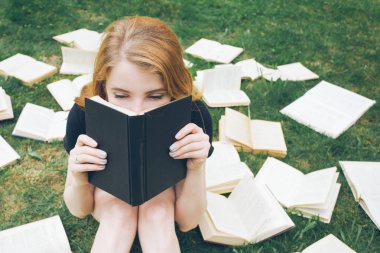 Genç kız çim yalan bir kitap okuma. Bir kız yaz bahçesinde kitaplar arasında