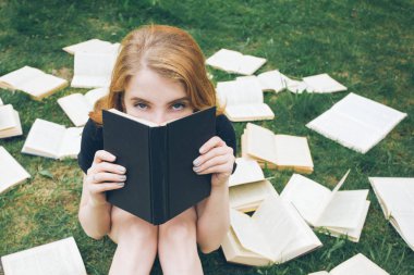 Genç kız çim yalan bir kitap okuma. Bir kız yaz bahçesinde kitaplar arasında
