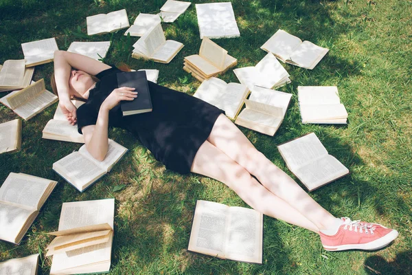 年轻的女孩躺在草地上看书。一个女孩在夏天花园里的书 — 图库照片