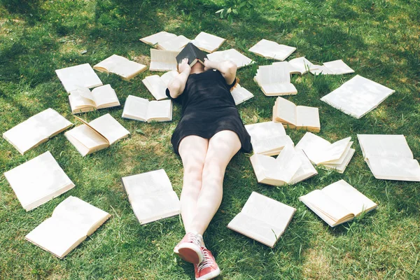 Jong meisje het lezen van een boek tijdens het liggen in het gras. Een meisje tussen de boeken in de zomertuin — Stockfoto